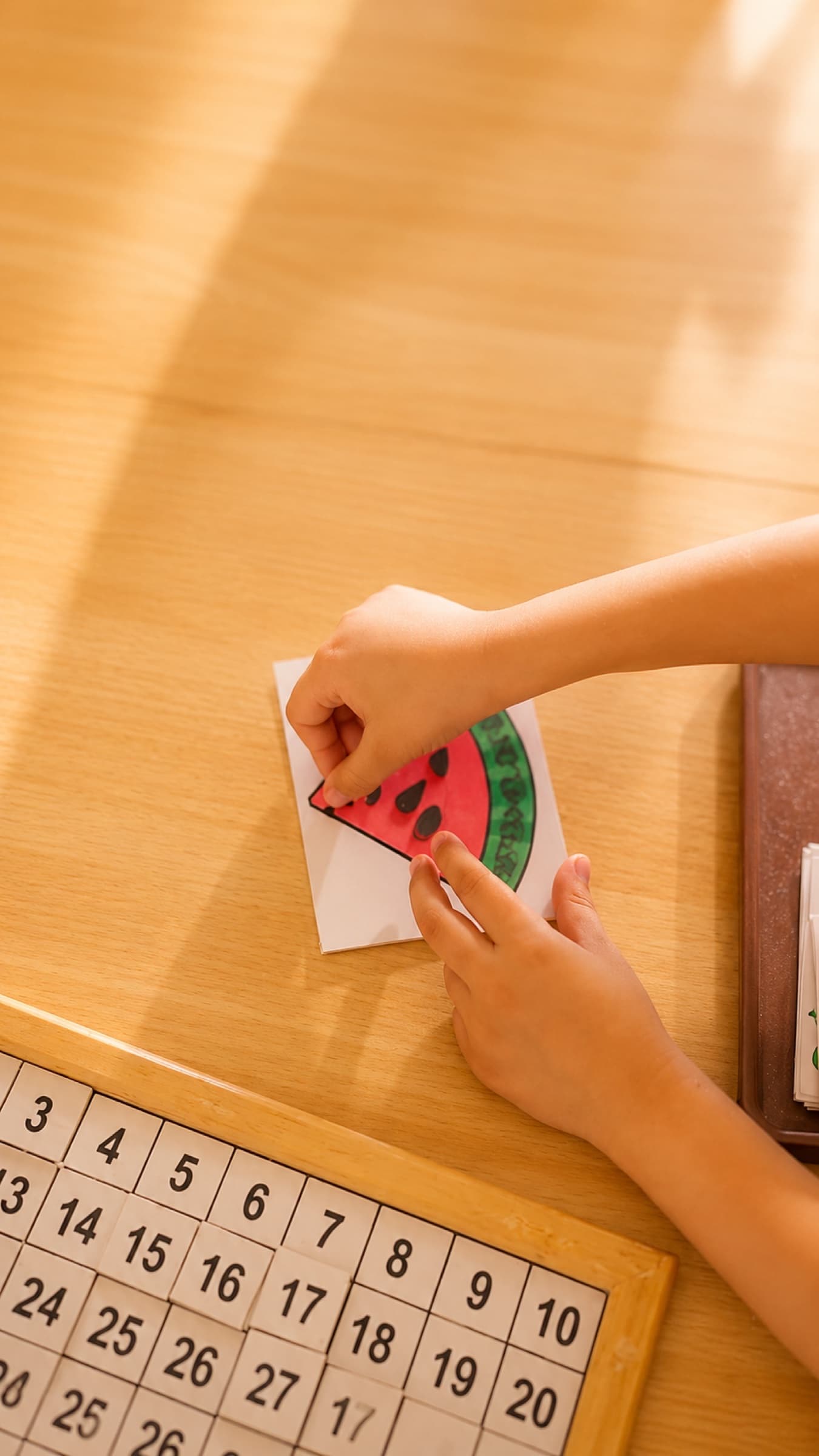 A child working with a Montessori hundred-board and counting card