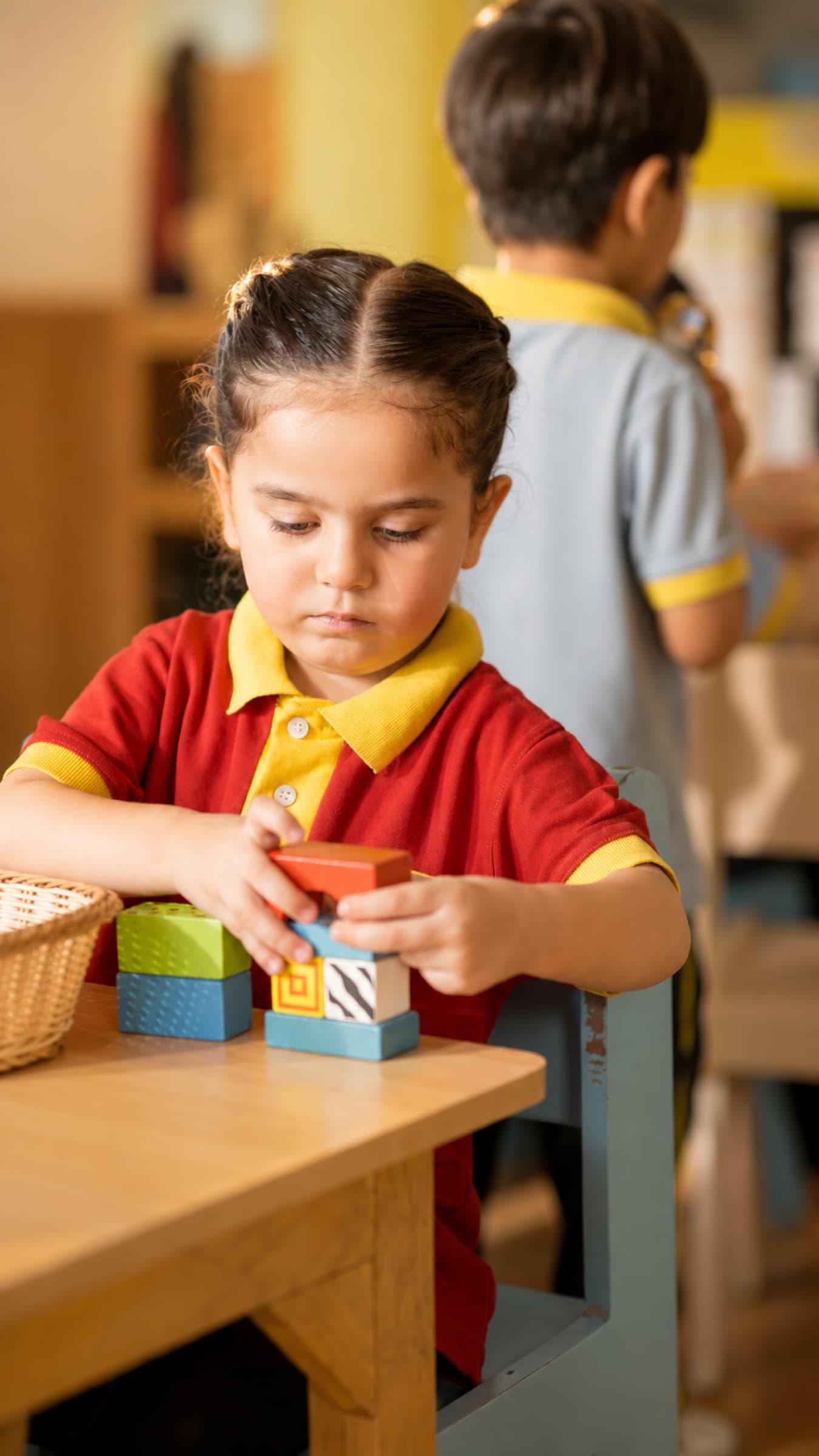 A child stacking blocks at the classroom table