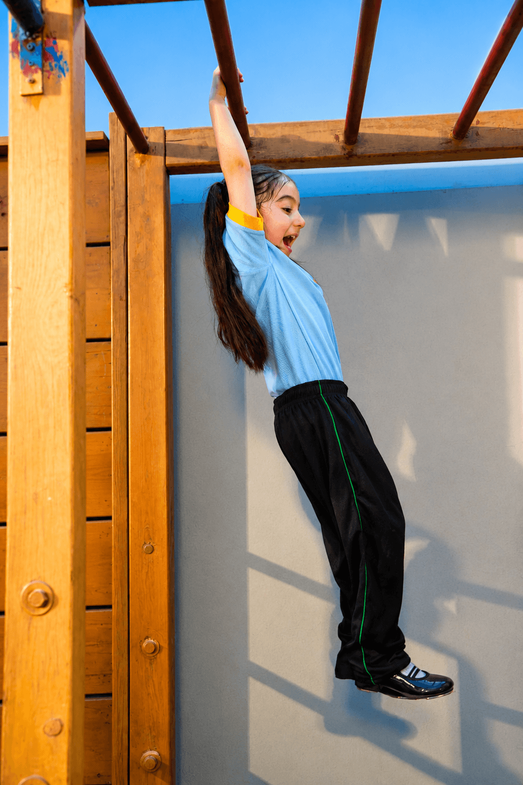 An Aster student playing on monkey bars outdoors