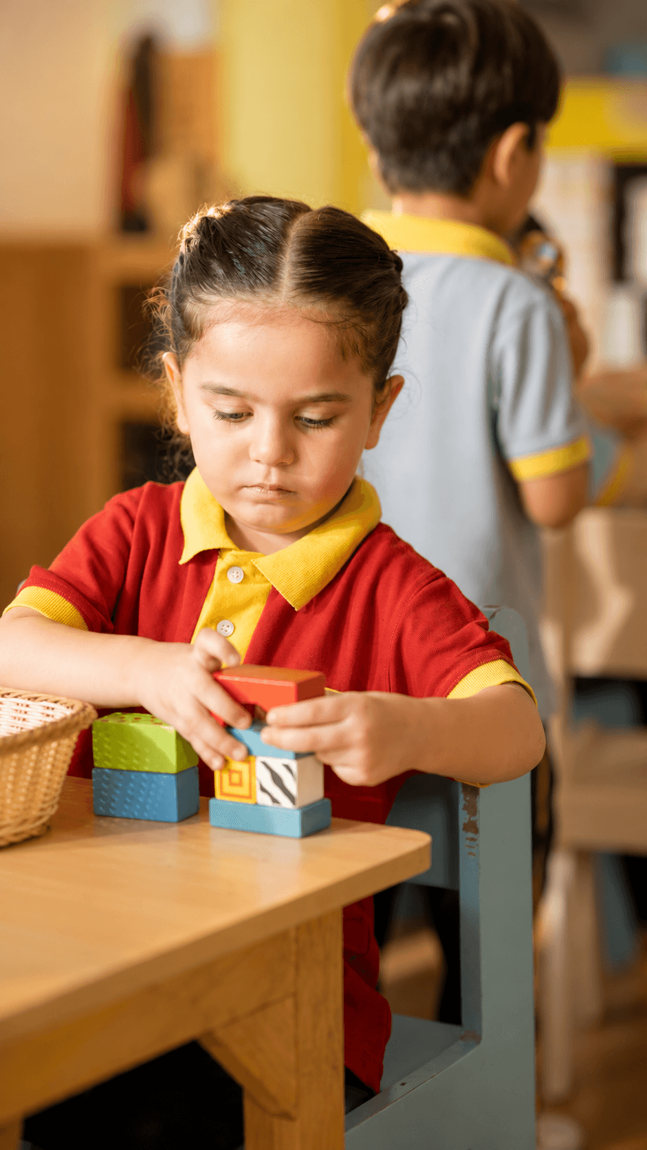 A child stacking blocks at the classroom table