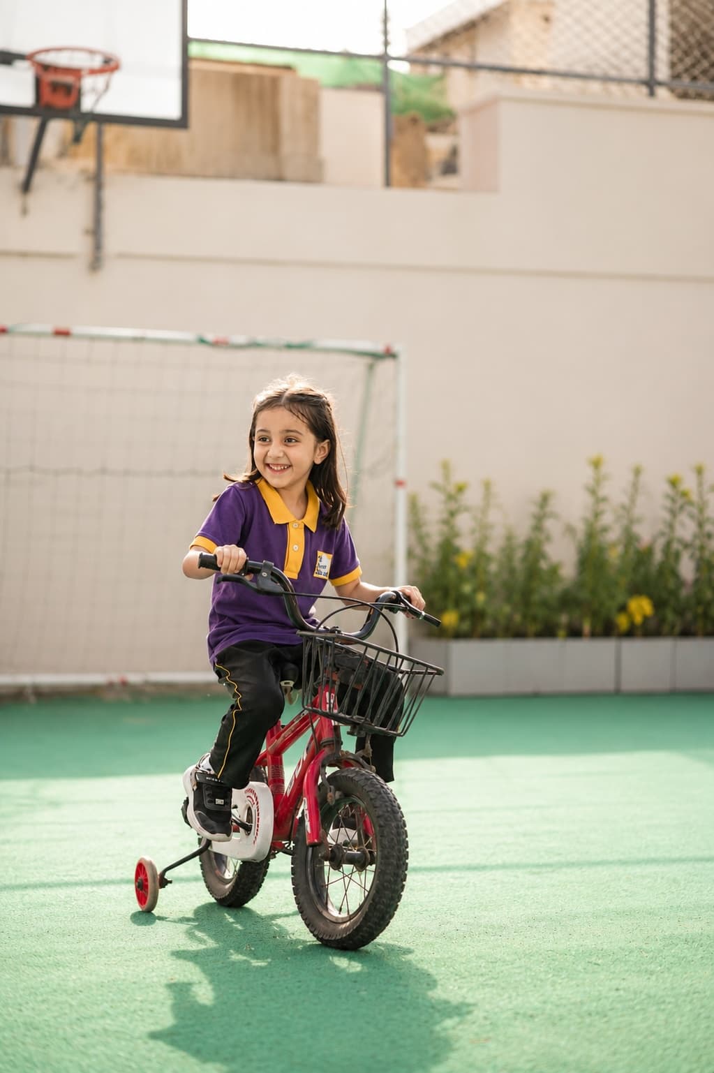 A child learning to ride a bike on the school playground