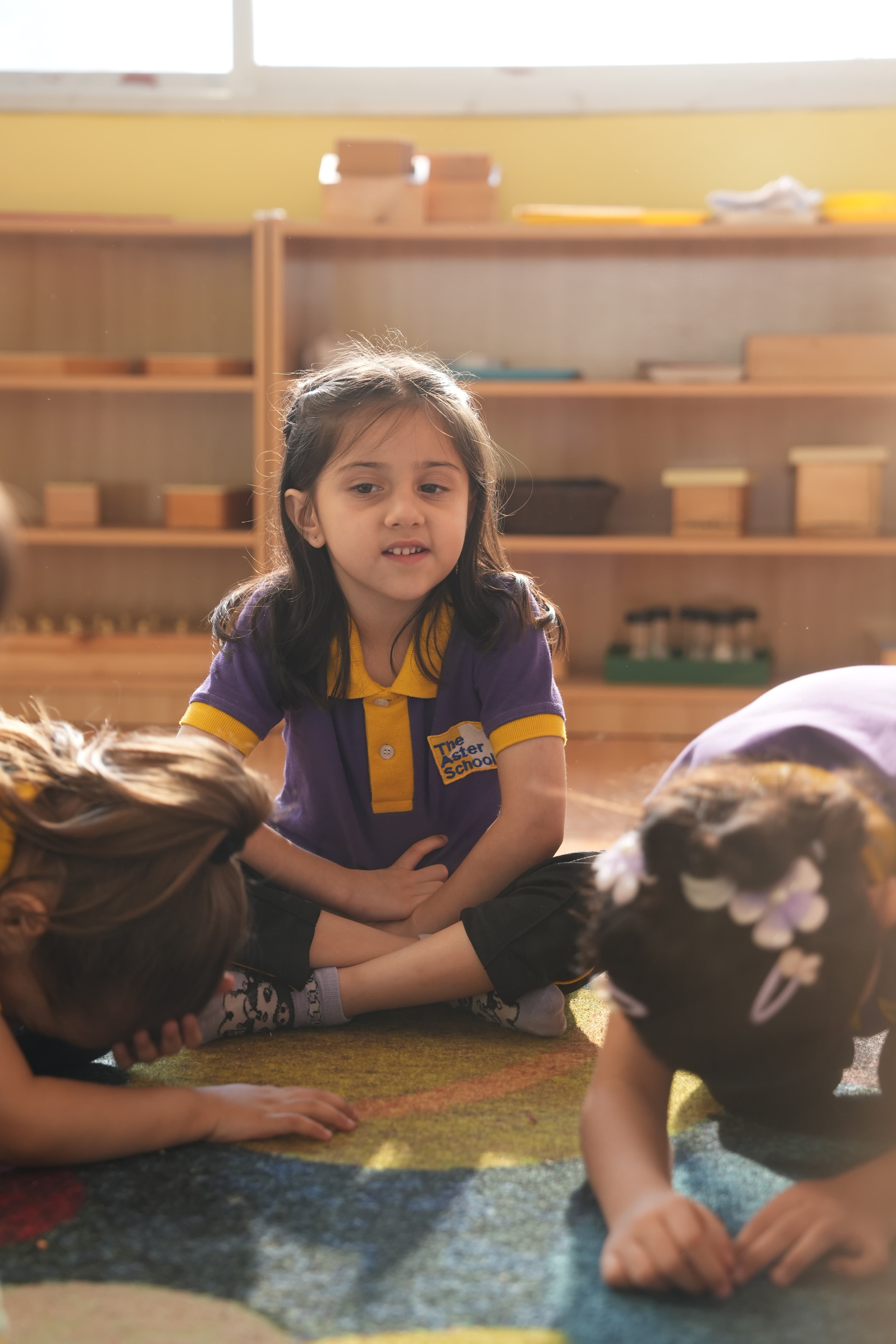 A child sitting cross-legged on the classroom floor