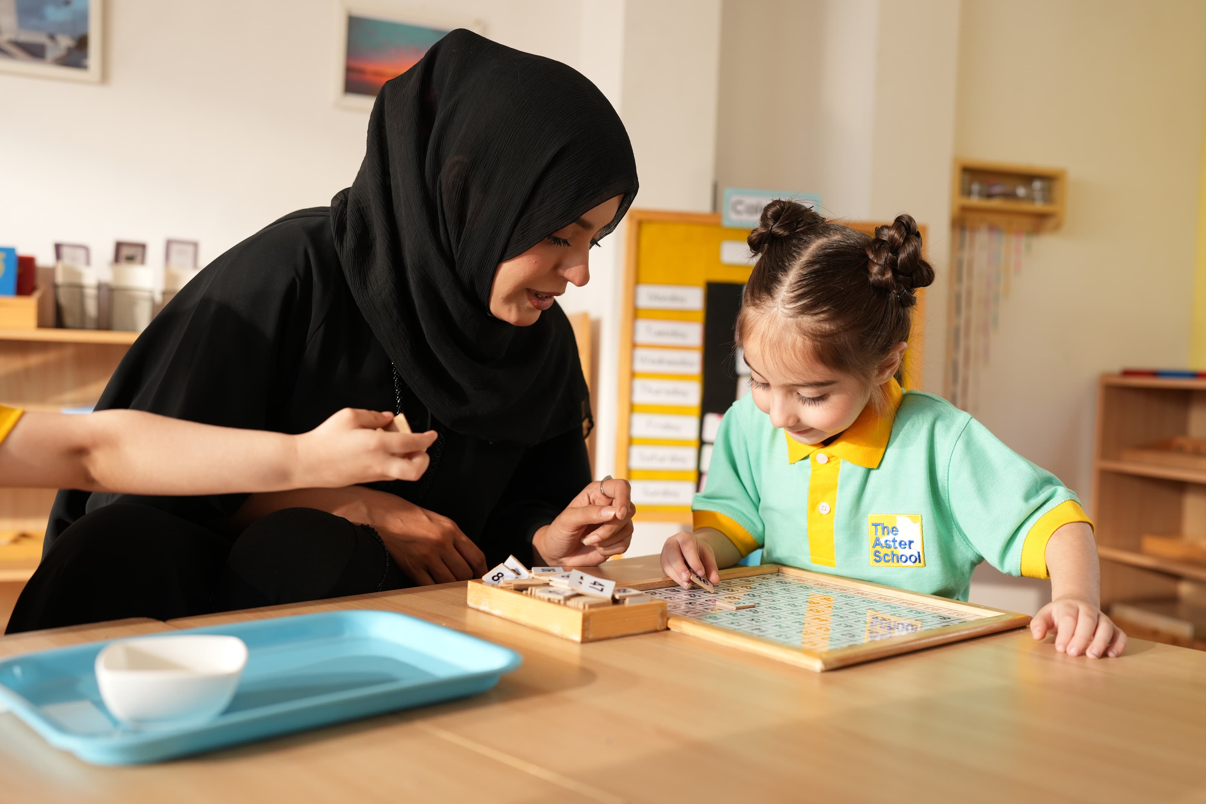 An Aster educator with a young child in a safe classroom setting